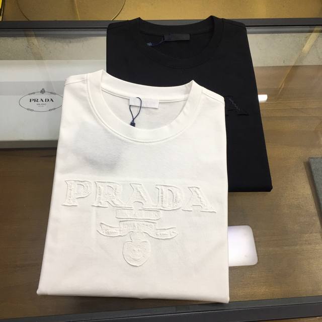 专柜新品 Prad... 黑色S-2xl，白色M-2xl 2024春夏新款男女同款短袖T恤，专柜同步发售！定制专属高克重精梳纯棉面料，定制原版工艺螺纹，胸前重工