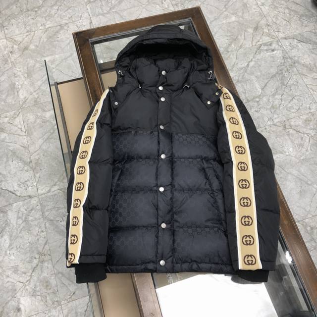 Gucci 古驰反光织带羽绒服 男女同款GG织带新元素暗双G 黑色立领羽绒大衣，采用尼龙塔夫绸绗缝设计，衣身缀有同色徽标。可拆卸式抽绳兜帽，正面隐藏式双向拉链，